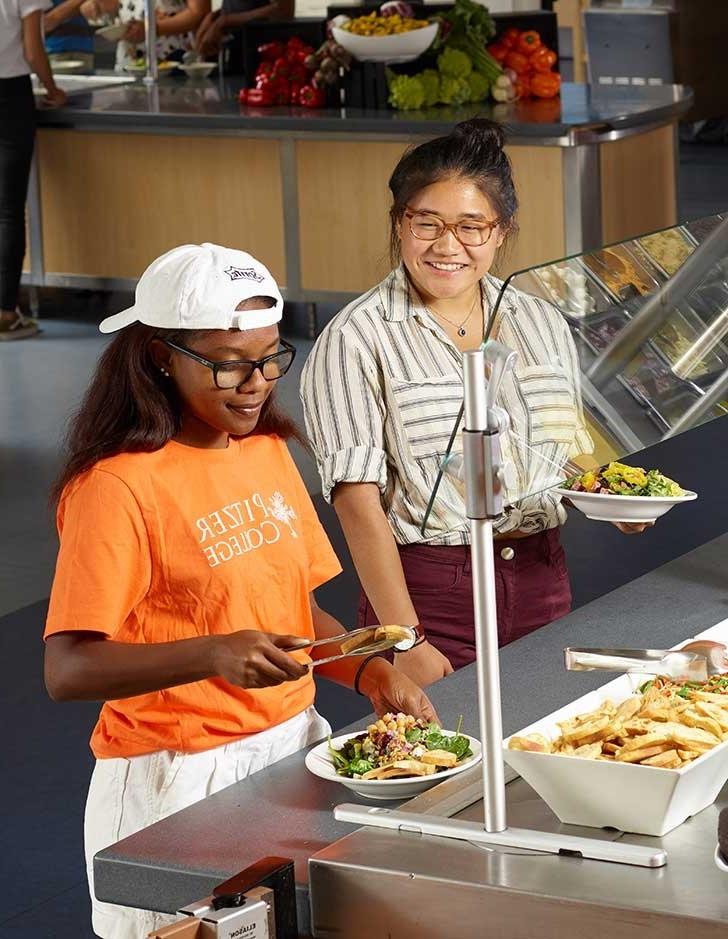 two students serve themselves at the salad bar in the pitzer dining hall